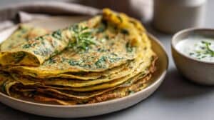 Slané chilla ze cizrnové mouky se špenátem a jogurtovým dipem na talíři