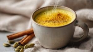 Hrnek zlatého mléka s kurkumou a zázvorem, jemná pára nahoře